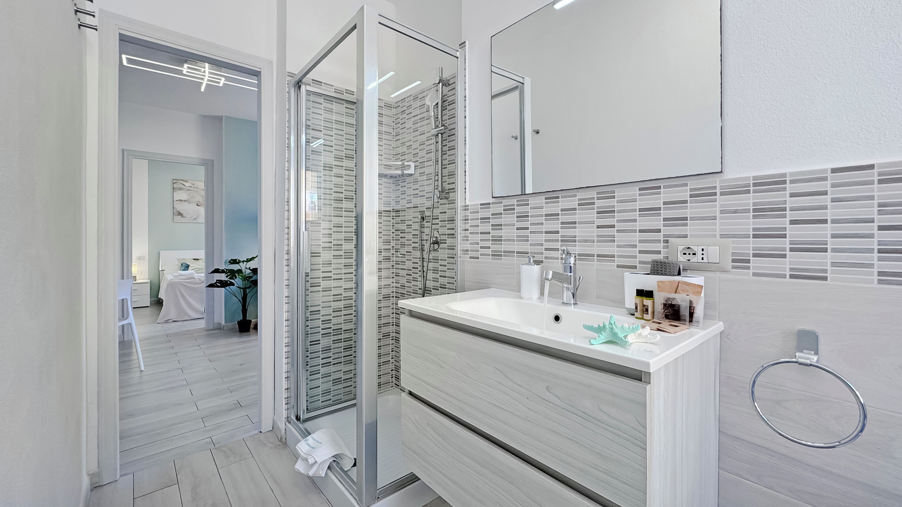 A modern bathroom with a glass shower enclosure, a white vanity, and a tiled backsplash.