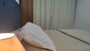 A hotel room with a bed, a bedside lamp, and a curtain. - Magnifico Apartamento Central (Curitiba)