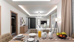 A modern dining area with a wooden table set for breakfast, including plates, cutlery, and a fruit bowl.