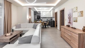 A modern living room with a sofa, a wooden coffee table, and a dining area with a table and chairs.
