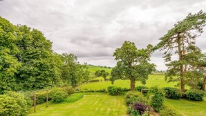 Un jardin luxuriant agrémenté d’une pergola en bois, d’une pelouse bien entretenue et d’une variété d’arbustes et de fleurs.