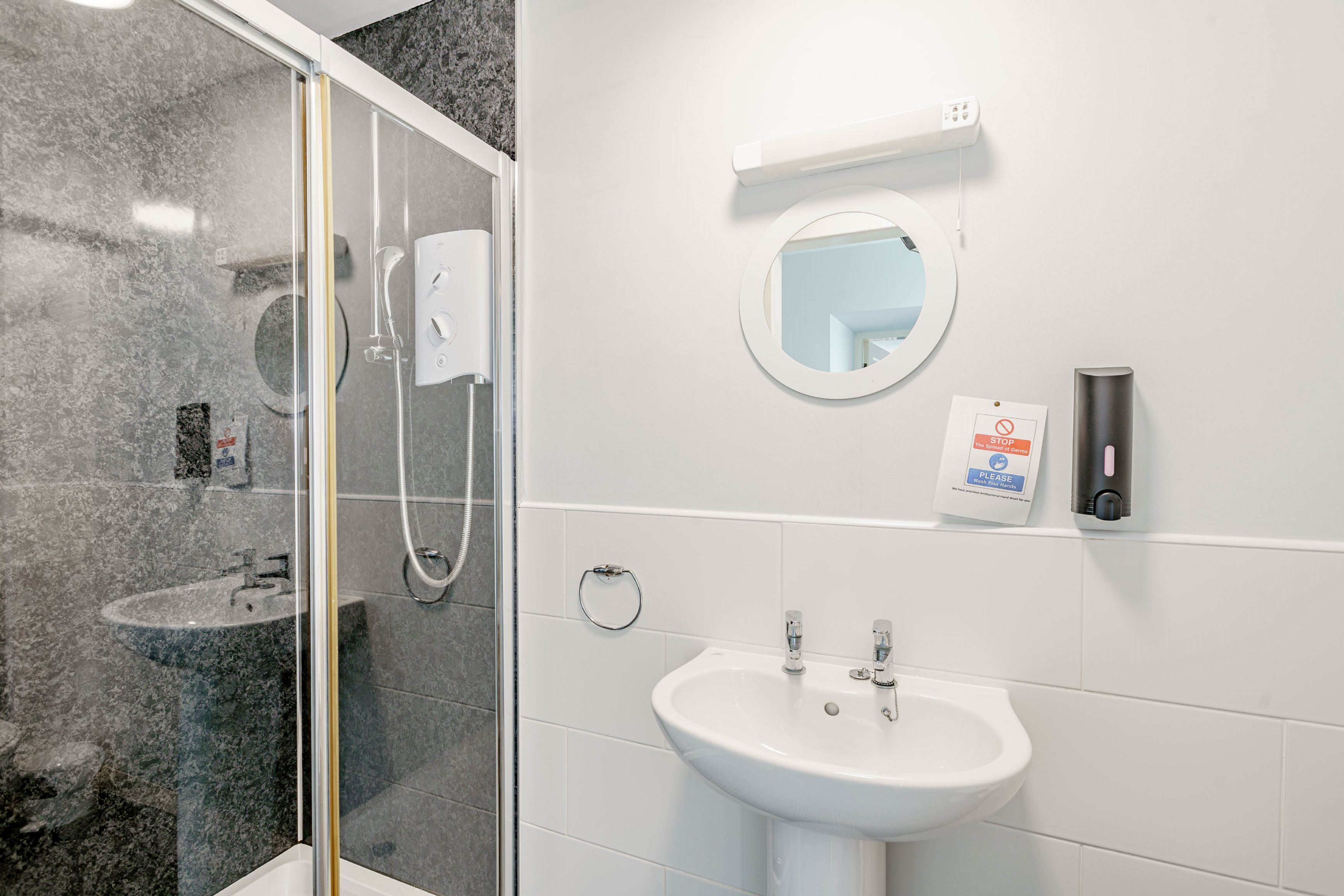Un baño moderno con cabina de ducha de vidrio, un lavabo blanco y un espejo.
