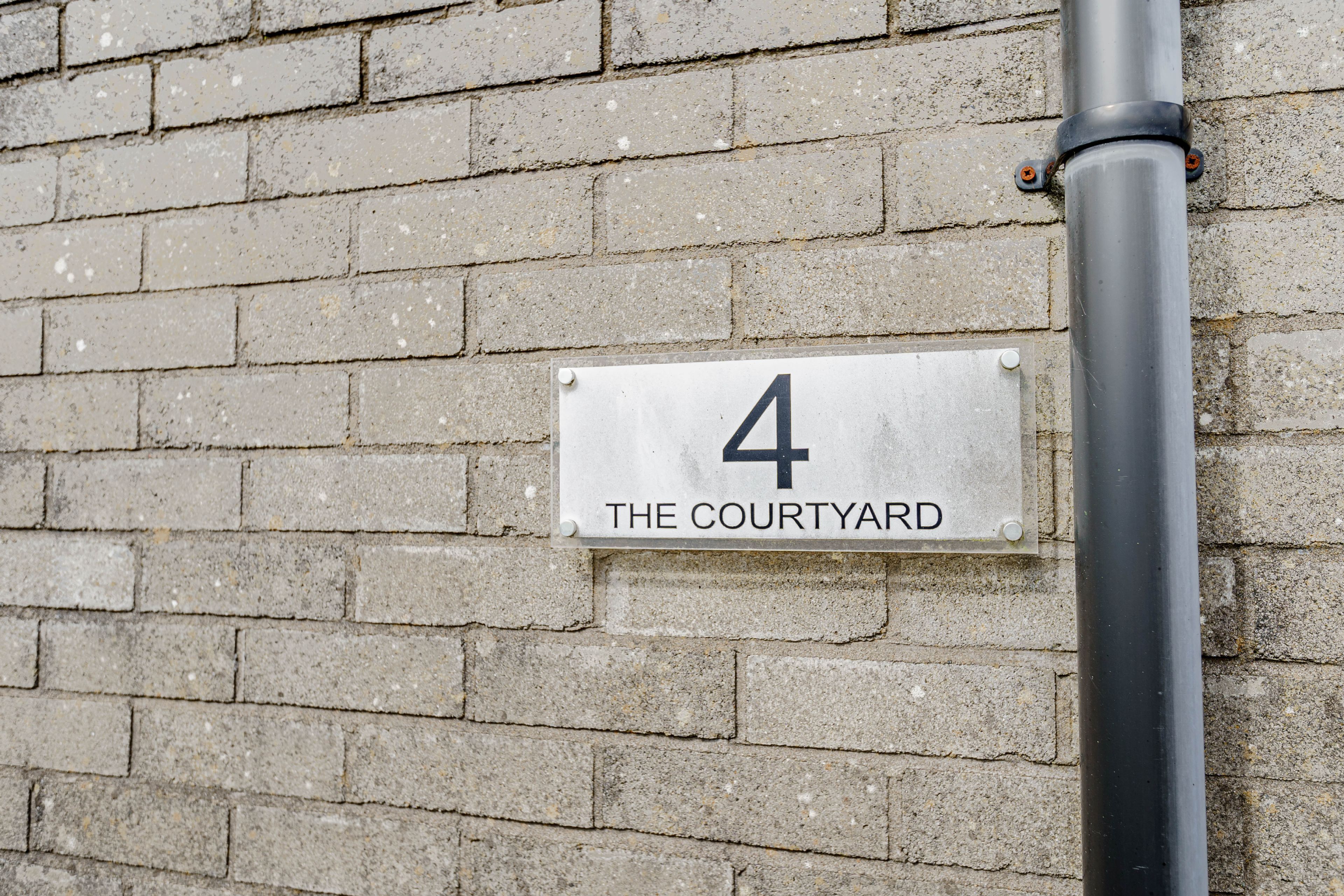 A sign on a brick wall indicating "4 THE COURTYARD".