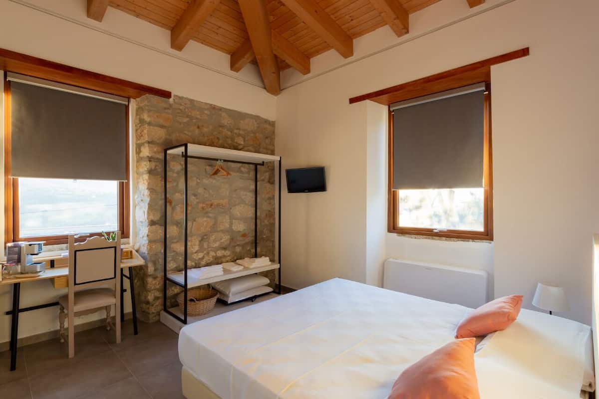Ein Schlafzimmer mit einem Bett, einem Schreibtisch, einem Stuhl, einem Fernseher und einer Steinwand.