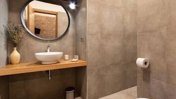 A modern bathroom with a round mirror, a beige sink, and a toilet.