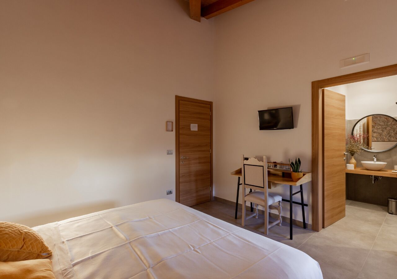 A bedroom with a bed, a desk, and a bathroom visible through an open door.