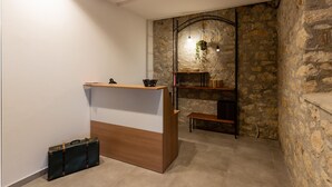 A reception desk with a wooden finish, a stone wall, and a hanging light fixture. - Tenuta San Martino (Nusco)