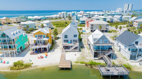 Un pueblo costero con propiedades frente al mar, incluyendo casas con balcones y un muelle que se adentra en el agua.