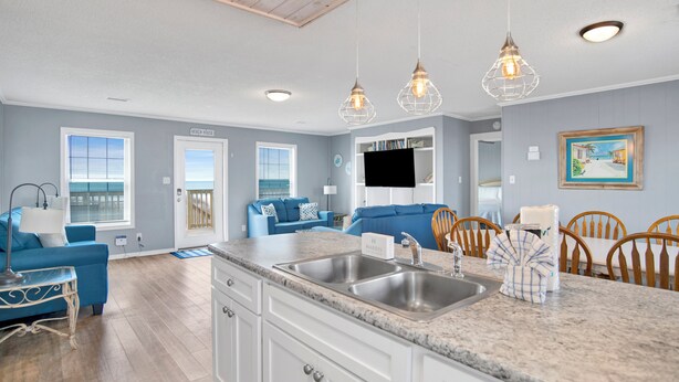 A modern kitchen with granite countertops, white cabinetry, and a double sink. - Gulf Front | Pet Friendly | Fort Morgan Retreat (Gulf Shores)