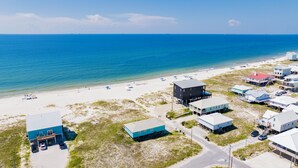 An aerial view of a coastal area with a beach, several buildings, and a clear blue sky. - Gulf Front | Pet Friendly | Fort Morgan Retreat (Gulf Shores)