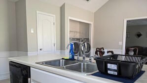 Una cocina con dos fregaderos, lavavajillas y zona de lavandería con lavadora.