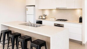 Une cuisine moderne dotée d’un îlot central, de tabourets de bar, d’un four encastré et d’une cuisinière à gaz.