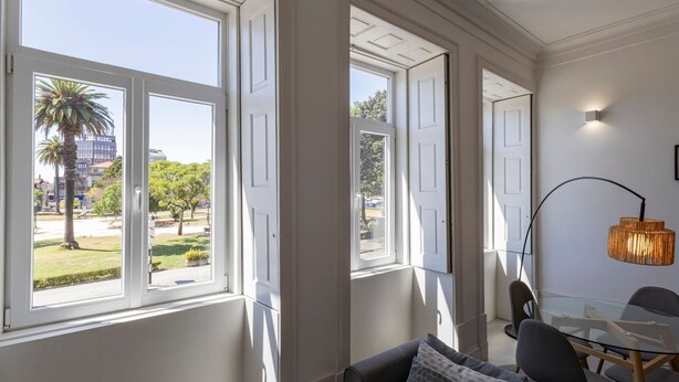 A room with large windows, a glass table, and a modern lamp.