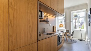 A modern kitchen with wooden cabinets, a built-in oven, and a window providing natural light.