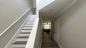 Escada que leva a um segundo andar, com um ventilador de teto e uma porta no final.