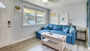Una sala de estar moderna con un sofá azul, una mesa de centro de madera y un ventilador de techo.