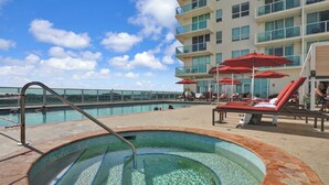 A swimming pool with a hot tub, red umbrellas, and lounge chairs. - The Harmony - Ocean & Relaxation (Miami)