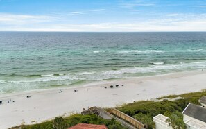 A beach with a wooden walkway leading to a building, a sandy shore, and the ocean.