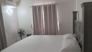 Una camera da letto con un letto, un comodino, una ventola e un armadio.