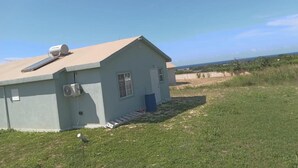 Un piccolo edificio a un piano con tetto spiovente, pannelli solari e una piccola finestra.