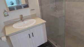 Un bagno con lavandino bianco, uno specchio e cabina doccia in vetro.