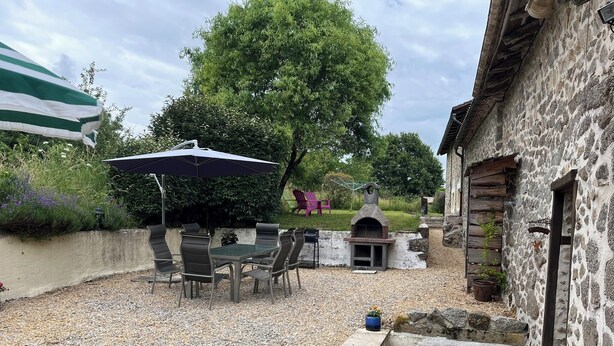 An outdoor patio area with a table and chairs, a barbecue grill, and a stone building. - La Petite Maison, charming 3 bedroom Gite in Saint-Estephe, 24360, Dordogne, (Saint-Estèphe)