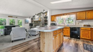 Une cuisine spacieuse avec des meubles en bois, un grand îlot central et un coin repas agrémenté d’un canapé gris.