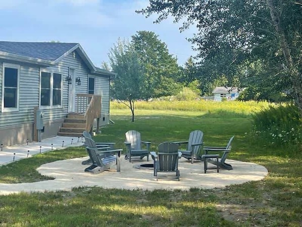 Ein Haus mit überdachter Terrasse, Sitzgelegenheiten im Freien und einem Rasen.