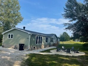 Ein eingeschossiges Gebäude mit Veranda, Sitzgelegenheiten im Freien und einem Schotterweg.