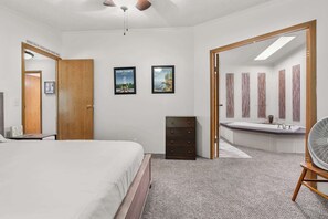 A bedroom with a bed, dresser, and a bathroom with a sink and mirror. - The Sweet Retreat: Newly Remodeled Sturgeon Bay Ho (Sturgeon Bay)