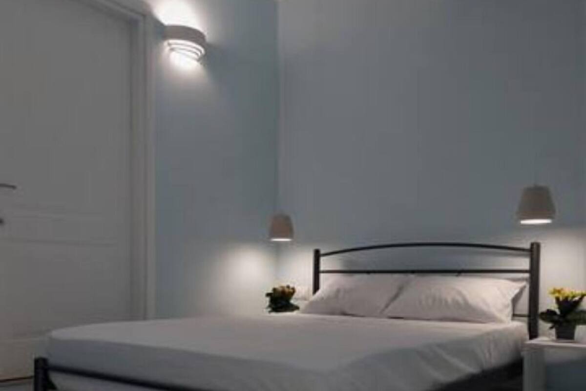 A bedroom with a bed, bedside tables, and wall-mounted lamps.