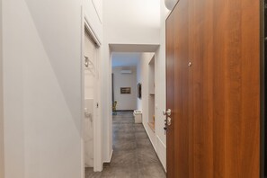 A narrow hallway with white walls, a wooden door, and a tiled floor. - Palazzo Falcone Apartments (Palermo)