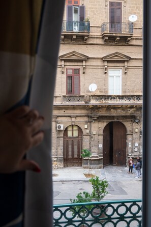 A view of a building with a large wooden door and a balcony with a metal railing. - Palazzo Falcone Apartments (Palermo)