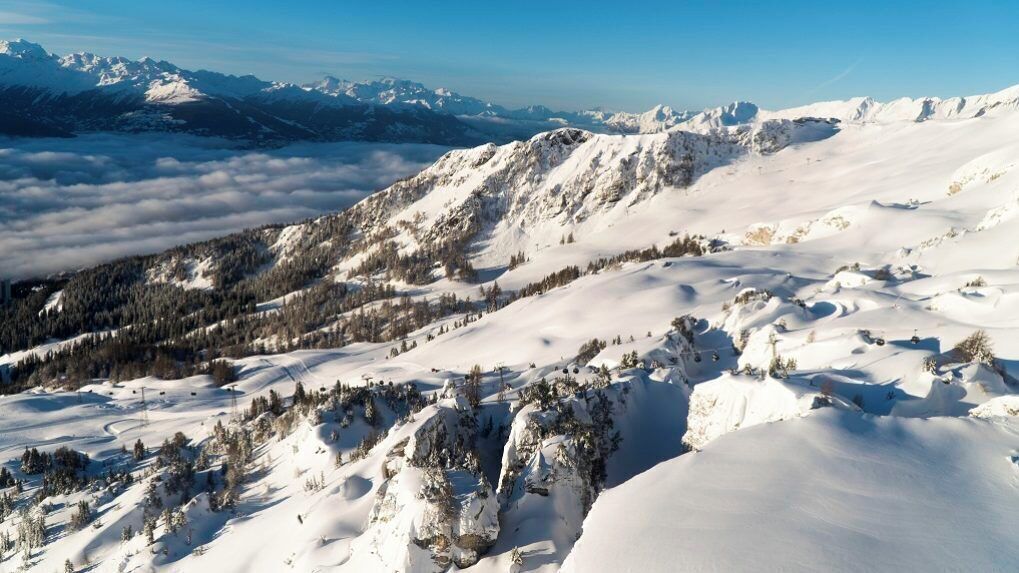A panoramic view of a snow-covered mountain range with a clear sky.