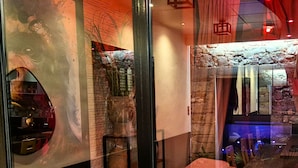 A spa room with a massage table, a stone wall, and a view of the outside. - AKA LOVE ROOM (Lavaur)