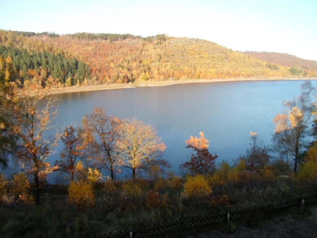 A lake surrounded by autumn-colored trees and a hilly landscape.