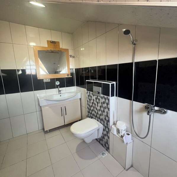 A modern bathroom with a white sink, toilet, and shower. - Esma Apart Otel (Alanya)