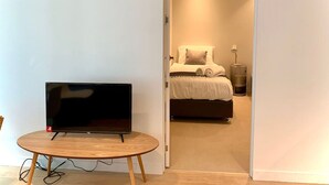 A room with a bed, a TV on a small table, and a door leading to another room. - Charming Dual-Unit Retreat on Elizabeth St (Melbourne)