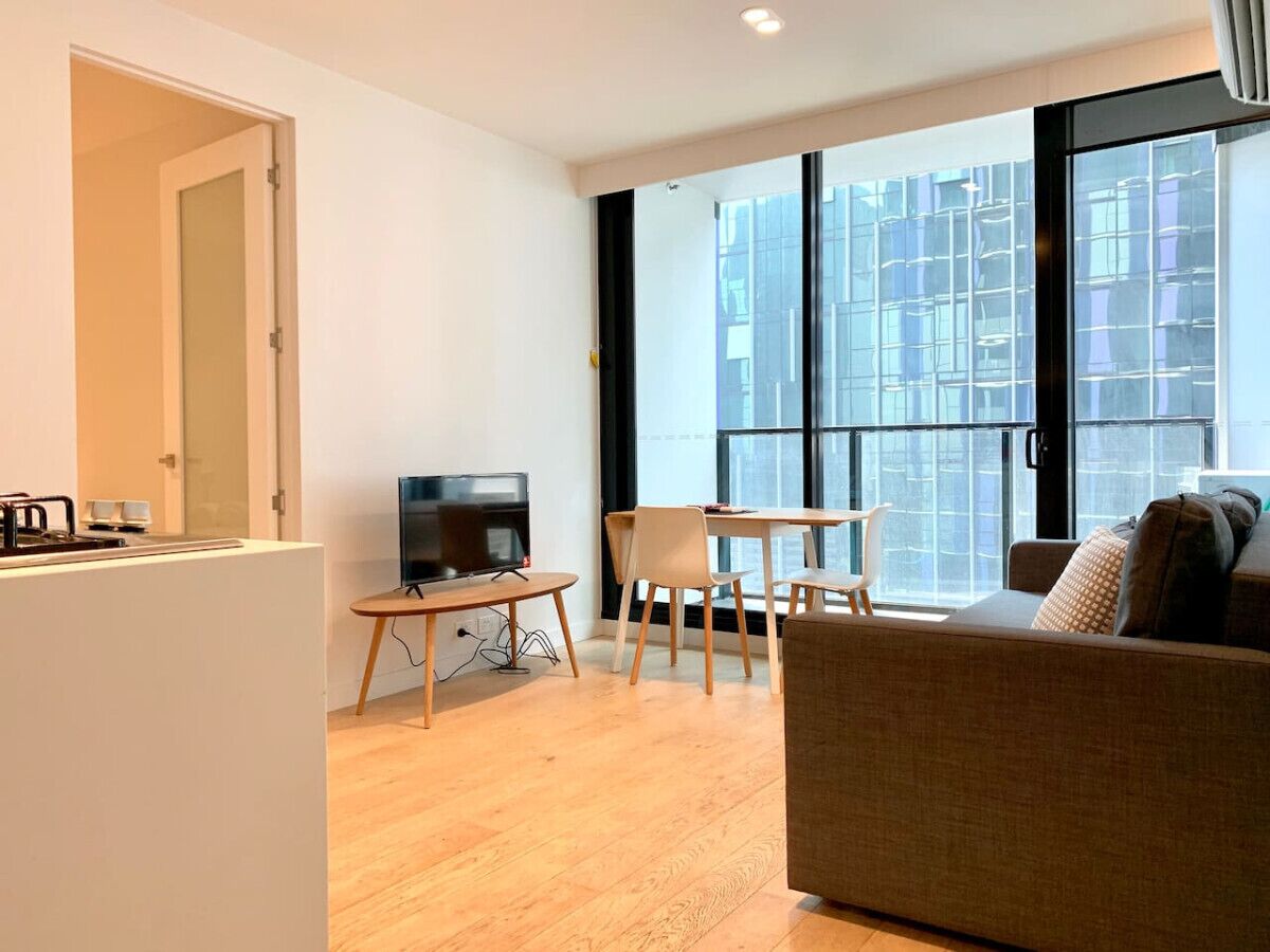 A modern living room with a flat-screen TV, a dining table, and a sofa.