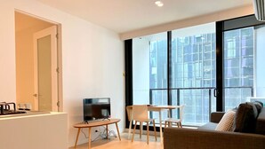 A modern living room with a flat-screen TV, a dining table, and a sofa. - Charming Dual-Unit Retreat on Elizabeth St (Melbourne)
