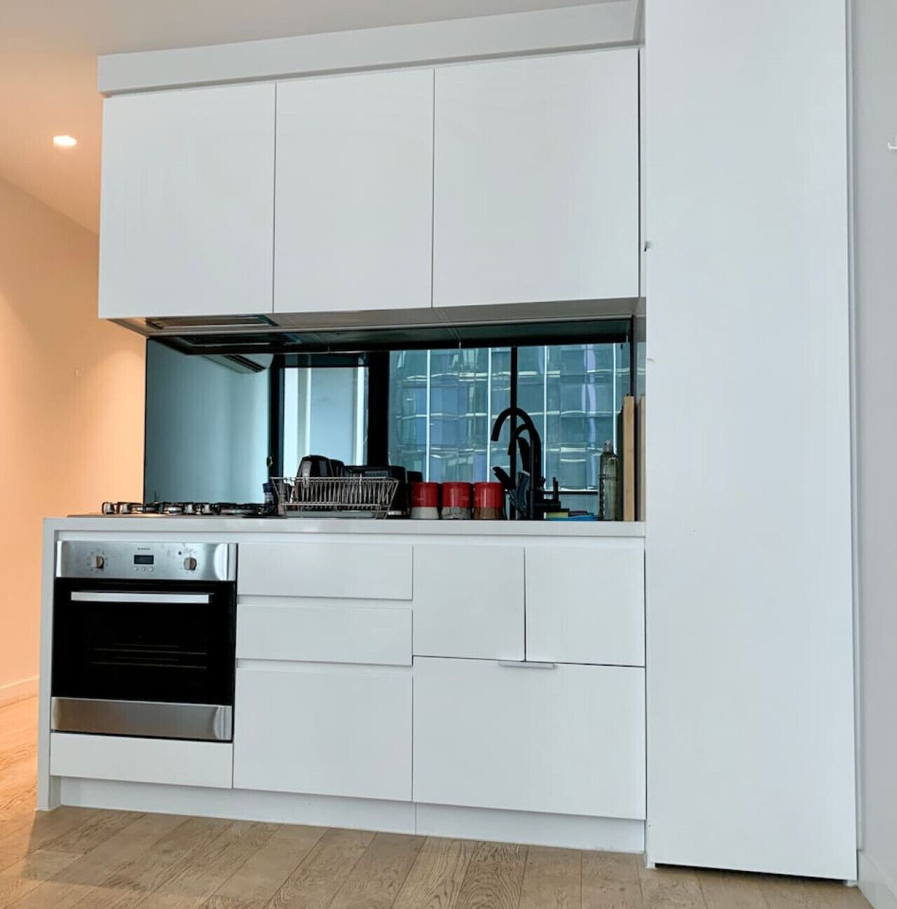 A modern kitchen with white cabinetry, a built-in oven, and a gas stove.