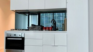 A modern kitchen with white cabinetry, a built-in oven, and a gas stove. - Charming Dual-Unit Retreat on Elizabeth St (Melbourne)