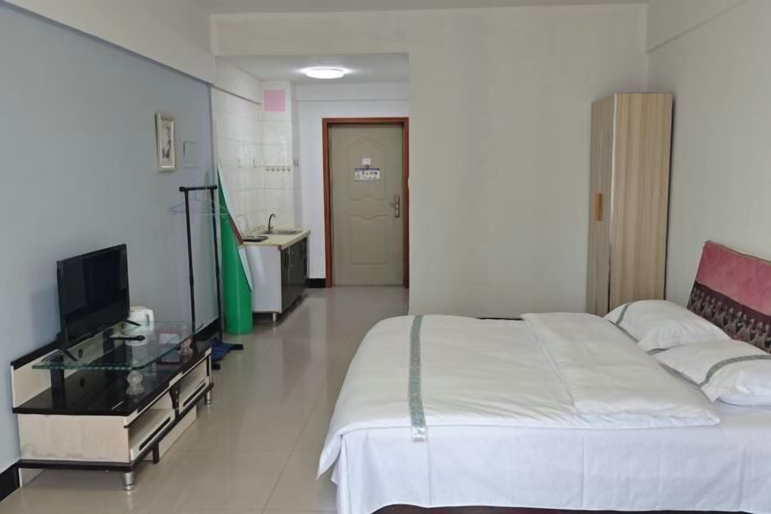 A hotel room with a bed, a television, a desk with a computer, a bathroom, and a wardrobe.