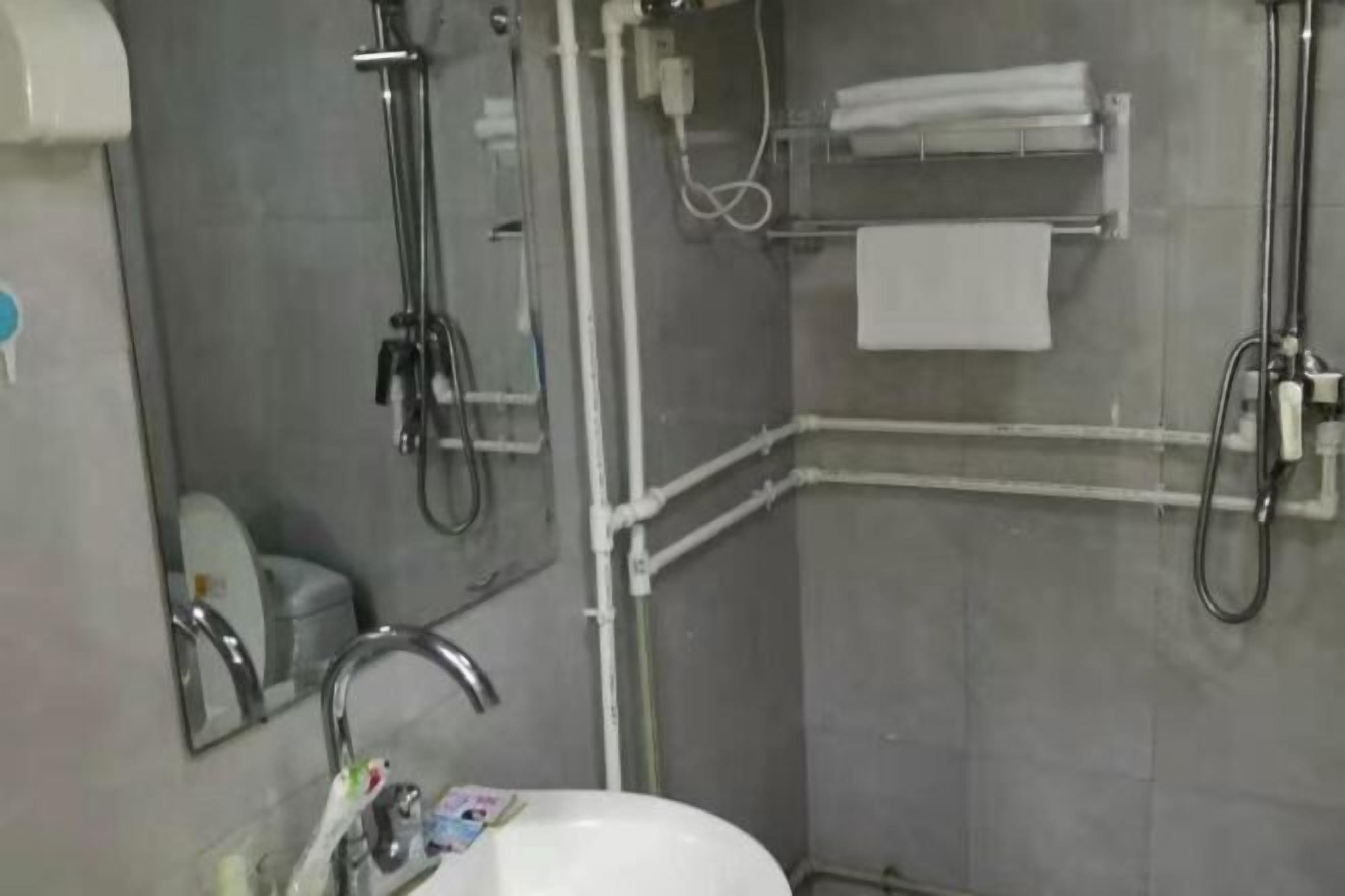 Une salle de bain équipée d’un lavabo, d’un miroir, d’un porte-serviettes et d’une douche.
