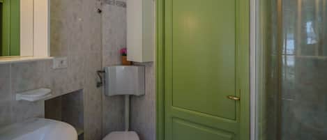 A bathroom with a toilet, sink, and a green door.