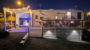 Een ruime camper met een overdekt terras, een eethoek en een zichtbare keuken.