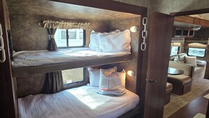 Een stapelbed met een raam, een klein tafeltje en een bank in een gezellig interieur.