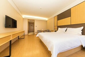 A modern hotel room with a large bed, a flat-screen TV mounted on the wall, a wooden desk, and a small table. - JI Hotel (Zhengzhou Xinzheng International Airport) (Xinzheng)