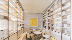 Een modern interieur met een centraal zitelement, boekenkasten en een kunstwerk in een lijst aan de muur.