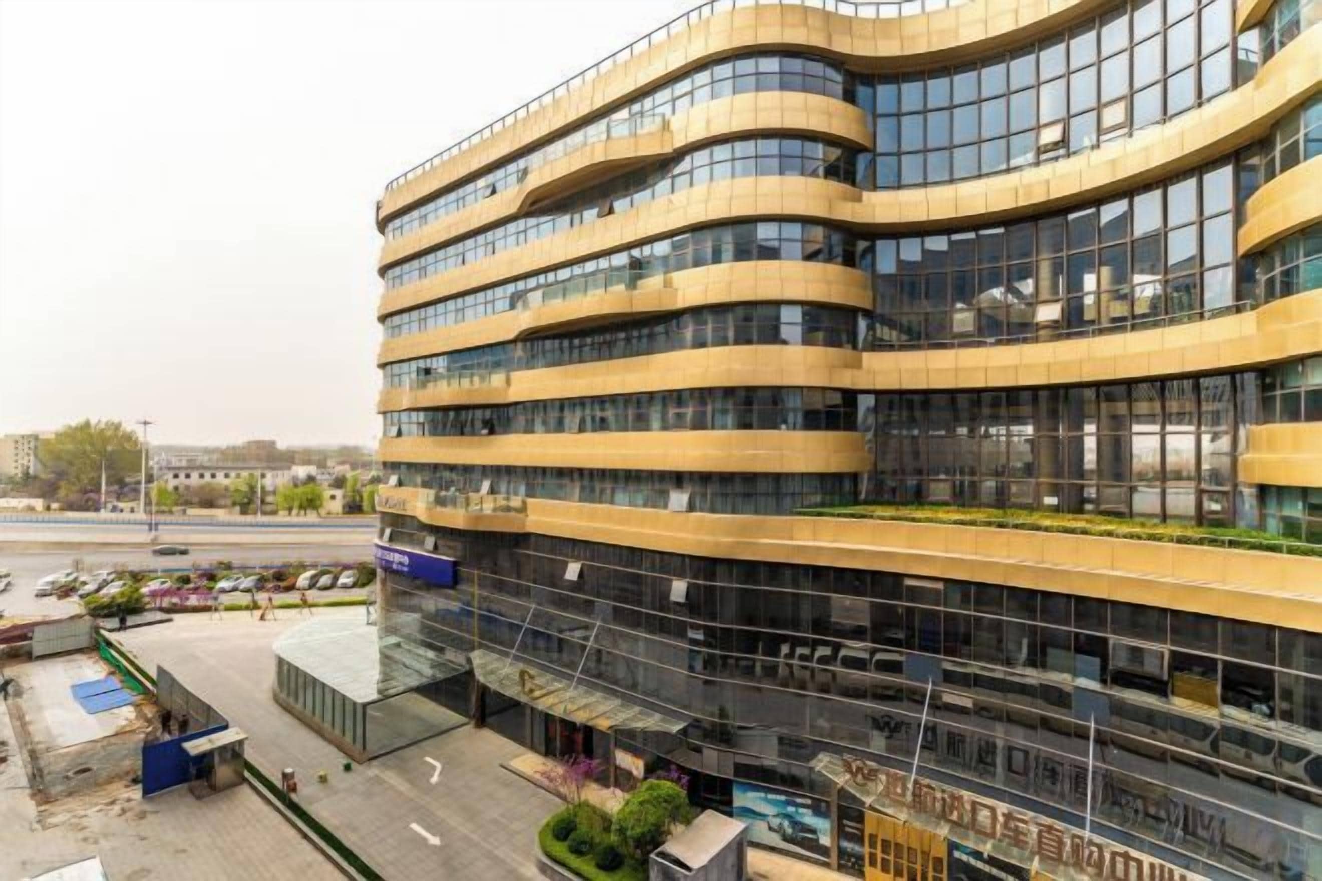 A multi-story building with a curved facade, large windows, and a ground-level commercial area.